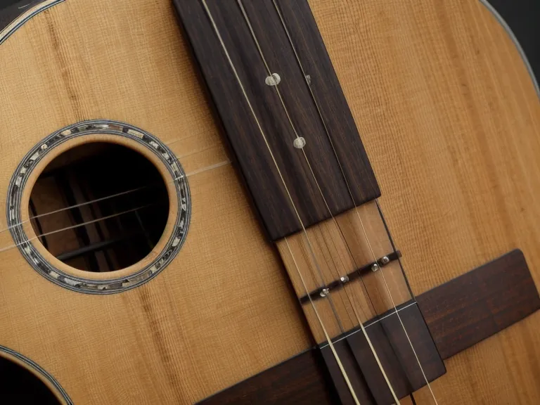 Guitarra acústica apoyada en una banca de madera dentro de una parroquia, lista para música de iglesia
