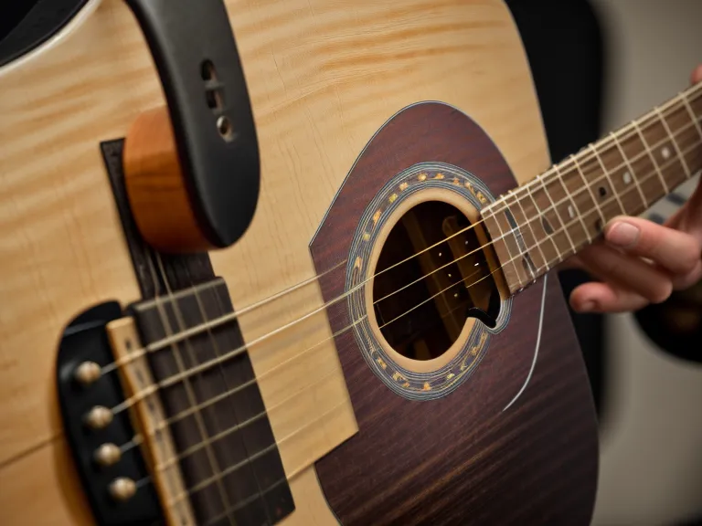 Detalle de la cejuela y las cuerdas de una guitarra acústica al practicar acordes con cejilla