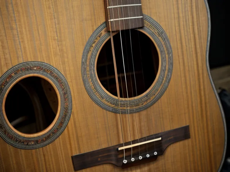 Primer plano de clavijas de plástico desgastadas en una guitarra acústica barata
