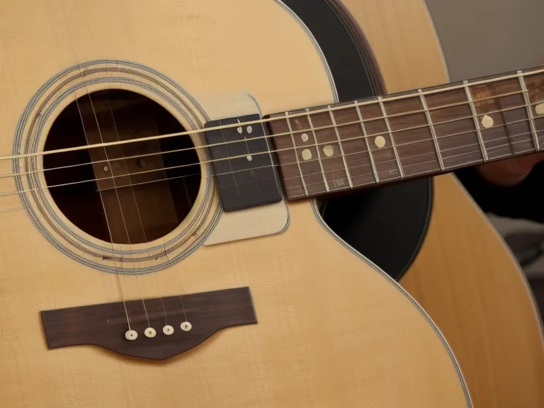 Guitarra acústica junto a un cancionero, curso de guitarra cristiana para principiantes adultos en sus primeras noches de rasgueo básico