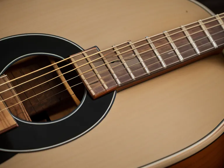 Guitarra acústica junto a una laptop con el curso Guitarra Master abierto, para aprender guitarra siendo adulto sin zumbido