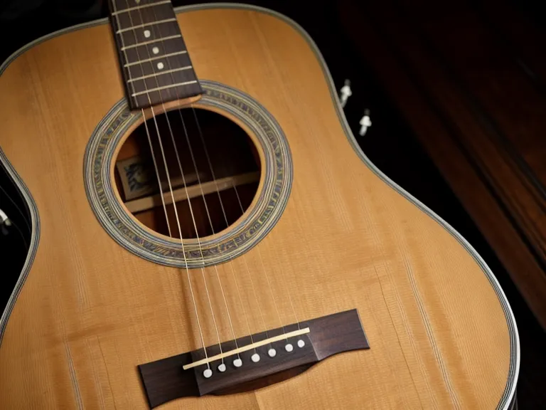 Mano de adulto practicando un cambio de acorde en el mástil, parte del progreso musical al aprender guitarra